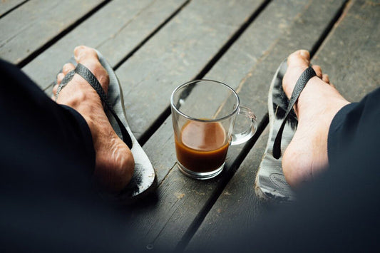 Feet with an iced coffee on wood