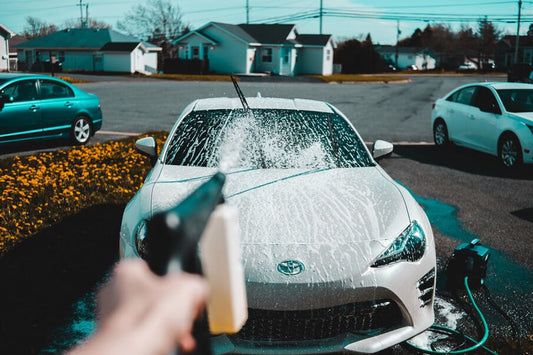 Hand spraying water on a car
